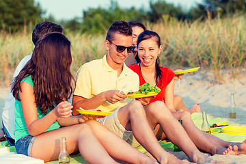 Image showing smiling friends sitting on summer beach