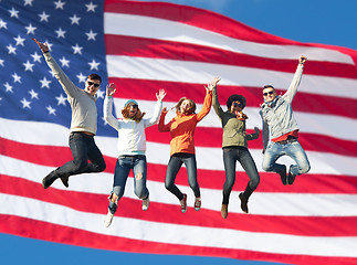 Image showing smiling friends in sunglasses jumping high