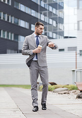 Image showing young serious businessman with paper cup outdoors