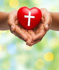 Image showing close up of hands holding heart with cross symbol