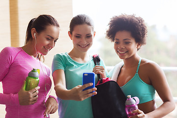 Image showing happy women with bottles and smartphone in gym