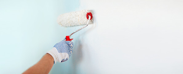 Image showing close up of male in gloves painting wall