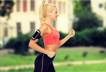 Image showing sporty woman running with smartphone and earphones