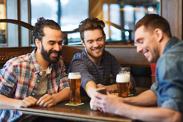 Image showing male friends with smartphone drinking beer at bar