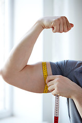 Image showing close up of male hands with tape measuring bicep