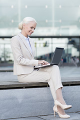 Image showing smiling businesswoman working with laptop outdoors