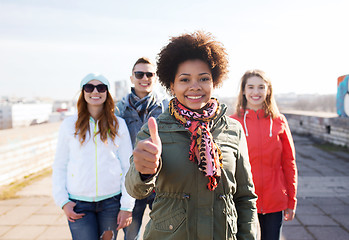 Image showing happy teenage friends showing thumbs up on street
