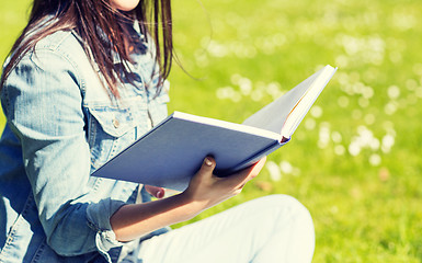 Image showing close up of smiling young girl with book in park