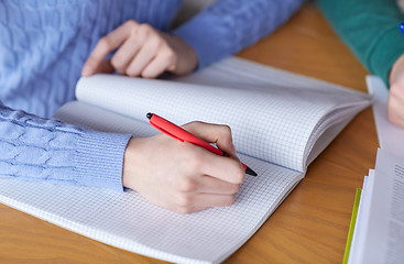 Image showing close up of student hands writing to notebook