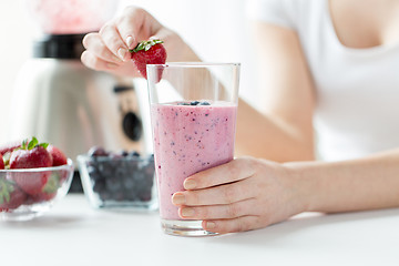 Image showing close up of woman with milkshake and strawberry