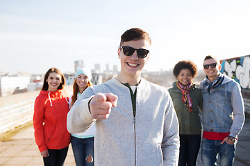 Image showing happy friends pointing finger to you on street