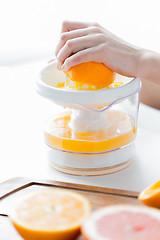 Image showing woman with squeezer squeezing orange juice at home