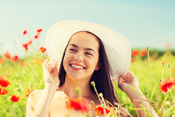 Image showing smiling young woman in straw hat on poppy field