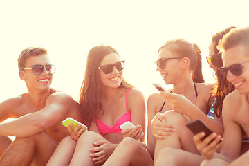 Image showing group of smiling friends with smartphones on beach