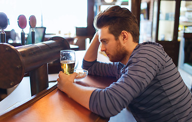 Image showing unhappy lonely man drinking beer at bar or pub