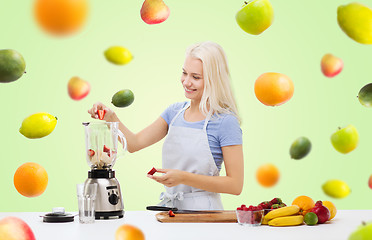 Image showing smiling woman with blender preparing shake