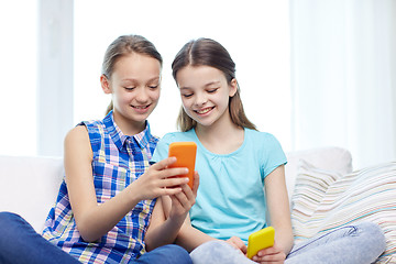 Image showing happy girls with smartphones sitting on sofa