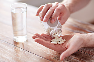 Image showing close up of man pouring pills from jar to hand