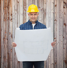 Image showing smiling male builder in helmet reading blueprint