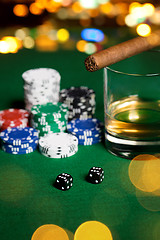 Image showing close up of chips, dice, whisky and cigar on table