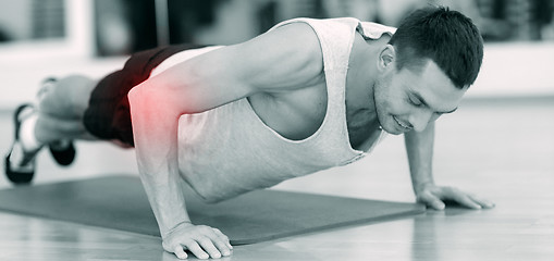 Image showing smiling man doing push-ups in gym