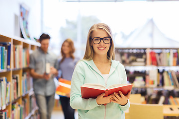 Image showing happy student girl or woman with book in library