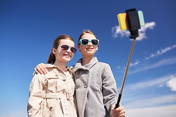 Image showing happy girls with smartphone selfie stick