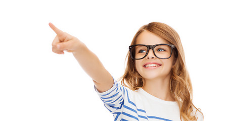 Image showing cute little girl in eyeglasses pointing in the air