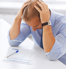 Image showing stressed businessman with papers at work