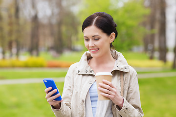 Image showing smiling woman with smartphone and coffee in park