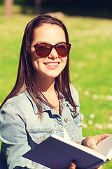 Image showing smiling young girl with book sitting in park