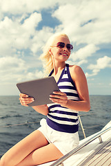 Image showing smiling woman sitting on yacht with tablet pc