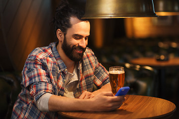 Image showing man with smartphone and beer texting at bar