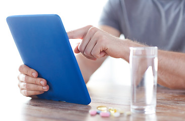 Image showing close up of hands with tablet pc, pills and water