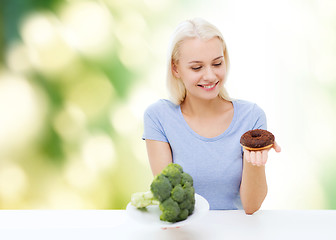 Image showing smiling woman with broccoli and donut