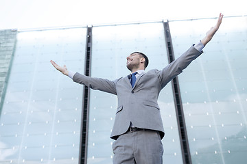 Image showing young smiling businessman over office building