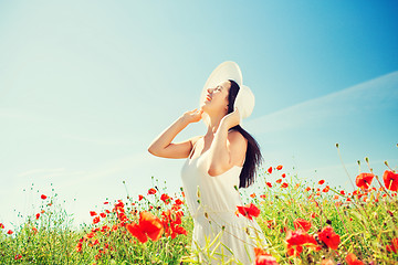 Image showing smiling young woman in straw hat on poppy field