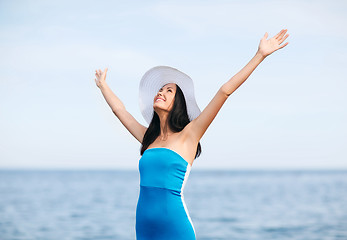 Image showing girl with hands up on the beach