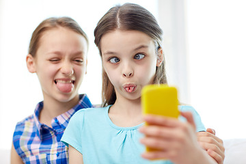 Image showing happy girls with smartphone taking selfie at home