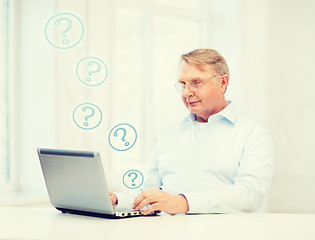 Image showing old man in eyeglasses working with laptop at home