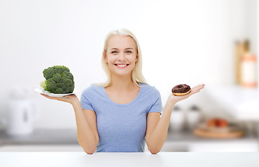 Image showing smiling woman with broccoli and donut on kitchen