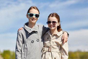 Image showing happy little girls in sunglasses hugging outdoors