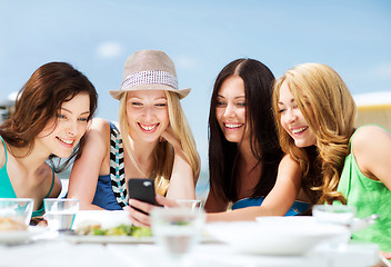 Image showing girls looking at smartphone in cafe on the beach