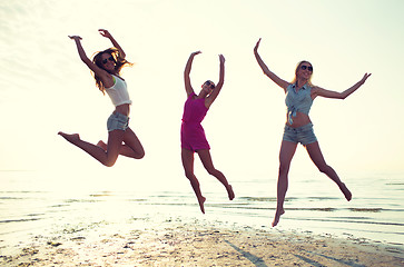 Image showing happy female friends dancing and jumping on beach