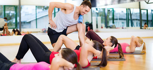 Image showing group of smiling women doing sit ups in the gym