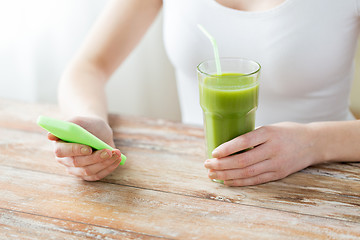 Image showing close up of woman with smartphone and green juice