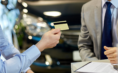 Image showing customer giving credit card to car dealer in salon