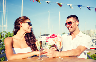 Image showing smiling couple with bunch and champagne at cafe