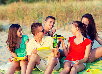 Image showing smiling friends sitting on summer beach