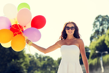 Image showing smiling young woman in sunglasses with balloons